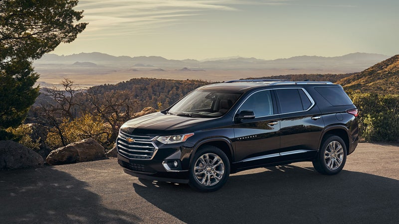 Front side view of a black 2018 Chevrolet Traverse SUV parked on a scenic overlook with mountains and valleys in the background.